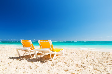 Fototapeta na wymiar Two yellow chairs on a beautiful Caribbean beach