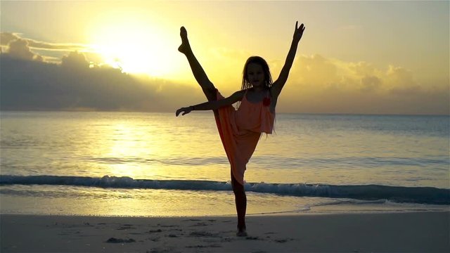 Adorable happy little girl have a lot of fun on white beach at sunset. SLOW MOTION