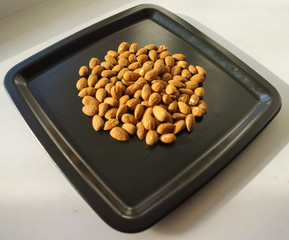 A bunch of nuts of almonds on a black plate. Close-up photo 