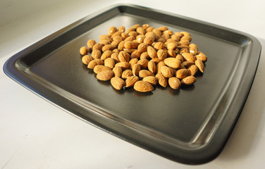 A bunch of nuts of almonds on a black plate. Close-up photo 