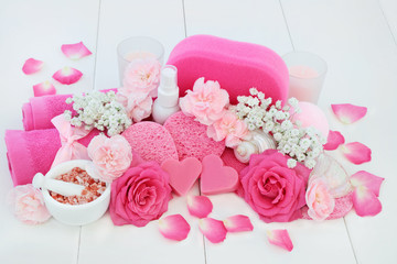 Spa beauty treatment products with a pink rose and carnation flowers, ex foliating salt, body lotion, heart shaped soap, sponges, wash cloths and seashells. Health spa concept.