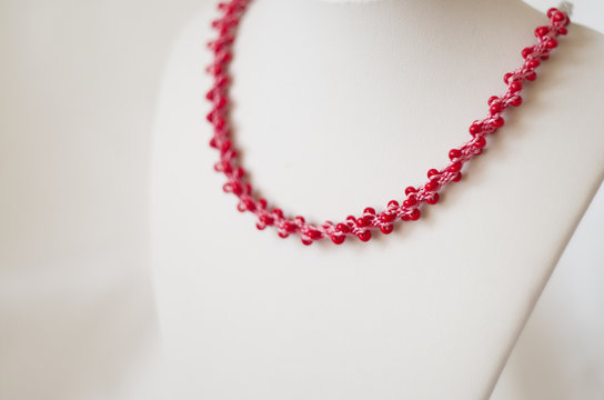 pink necklace with red beads on white stand