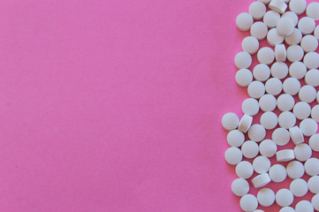 Large amount of white pills isolated on pink background with space for add text. Colorful pop photography: concept of medicine and human health.