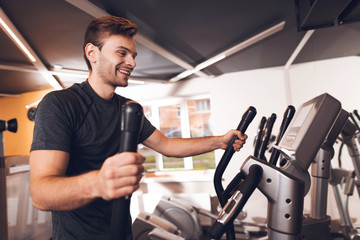 Fototapeta na wymiar A man in the gym. He leads a healthy lifestyle. A man is engaged in an elliptical trainer.