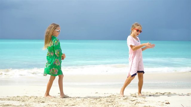 Adorable little girls have a lot of fun on the beach. Two beautiful kids dancing on the seashore