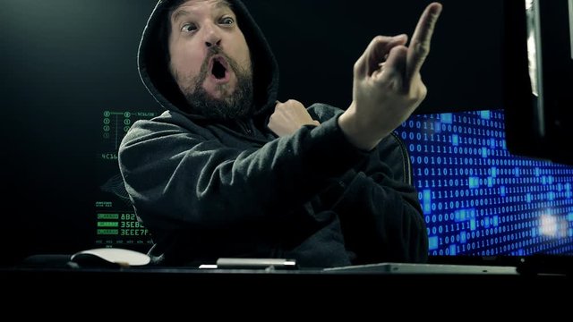 Cool hacker showing medium finger to screen sign of victory slow motion