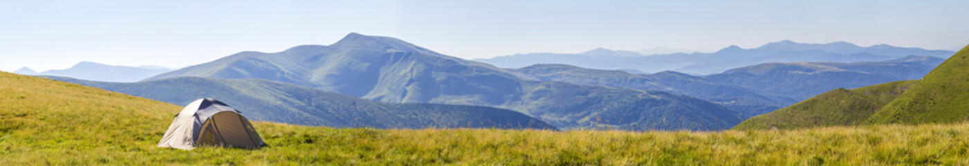 Mountain panorama with tourist tent. Sunrise or sunset in mountains. Hiking concept.