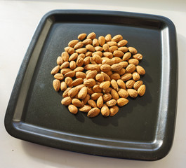 A bunch of nuts of almonds on a black plate. Close-up photo 