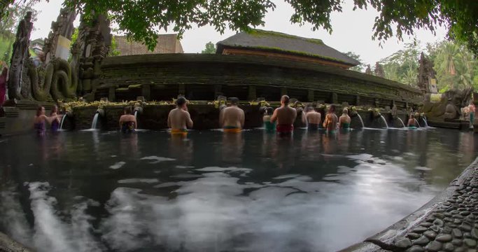 Group of devotional people taking bath at Bali Water Temple and offering flowers and prayers