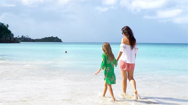Beautiful mother and daughter on Caribbean beach. Family walking on tropical seashore. SLOW MOTION