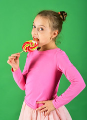 Girl eats big colorful sweet caramel. Treatment and sweets concept.