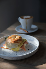 Bagel ham cheese in close up on wood background in coffee shop