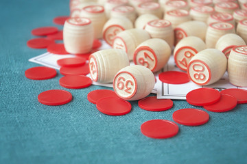 Wooden kegs and cards for a lotto on green background, selective focus.