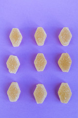 Top view on a yellow sweet marmalade with a purple background, flatlay