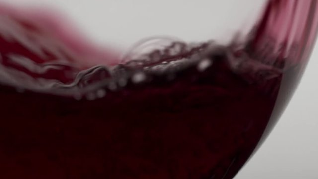 Red Malbec wind being poured into a glass in slow motion, stark white background. Passion style footage of Easter scenes