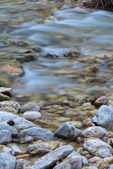 Sassi di un fiume in primo piano e acqua che scorre sullo sfondo