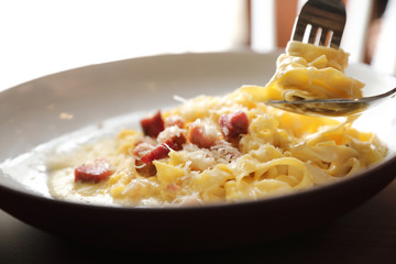 spaghetti carbonara white sauce with bacon on wood background in restaurant