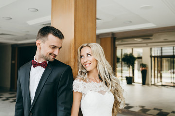 Smiling bride and groom are looking at each other with love. Wedding