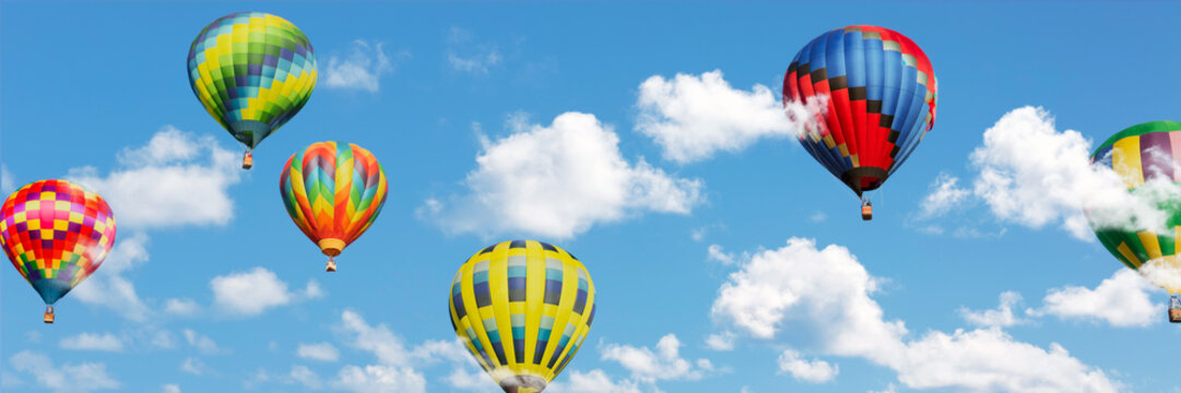Multi colored hot air balloons in white clouds over blue sky