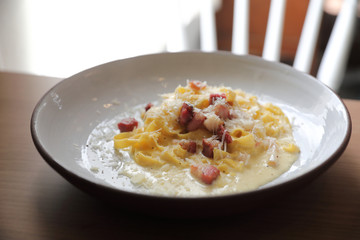 spaghetti carbonara white sauce with bacon on wood background in restaurant