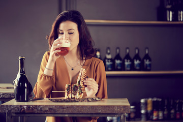 pretty woman eating club sandwich in a brewery 