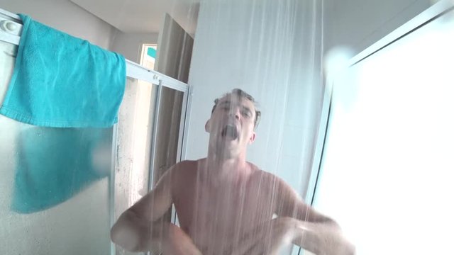 young handsome muscular man takes a shower. the guy washes, sings and dances in the shower. action camera. 4k