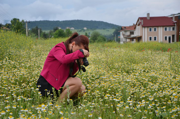 Woman is a professional photographer with dslr camera, outdoor and sunlight, daisy flovers garden,