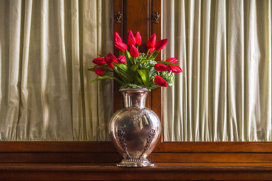 Silver Vase with Red flowers on Wooden Classical furniture