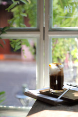 Ice black coffee with orange on wood background