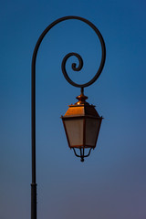 Fototapeta na wymiar Vintage iron lamp lantern on a curved pole> Blue sky in the background