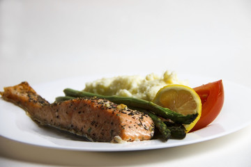 Cooked, fried, grilled salmon fish fillet with potatoes, asparagus, tomato and lemon slice on a...