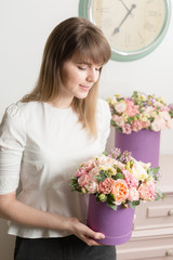 perfect gift or compliment. bouquet in lilac hatbox. beautiful luxury bunch of mixed flowers in womans hand. the work of the florist at a flower shop.