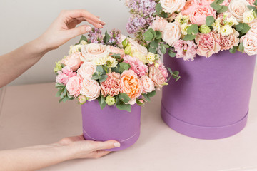 Selective focus on bouquet in lilac hatbox. beautiful luxury bunch of mixed flowers in womans hand. the work of the florist at a flower shop. perfect gift or compliment.