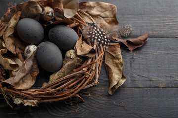 Black eggs in a nest of dry branches on a black board. Easter style.