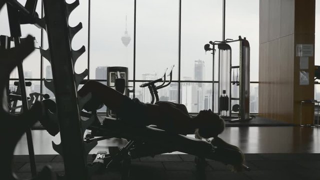 Sportswoman doing situps in gym. Muscular female athlete doing abs workout. Silhouette of slim athletic girl. Active and healthy lifestile concept.