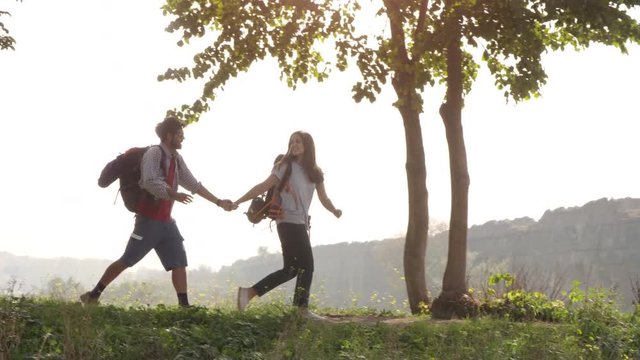 Young lovely couple backpackers tourists walking holding hands arrive on hill in front of roman aqueduct arches in parco degli acquedotti park ruins in rome on romantic misty sunrise with guitar and