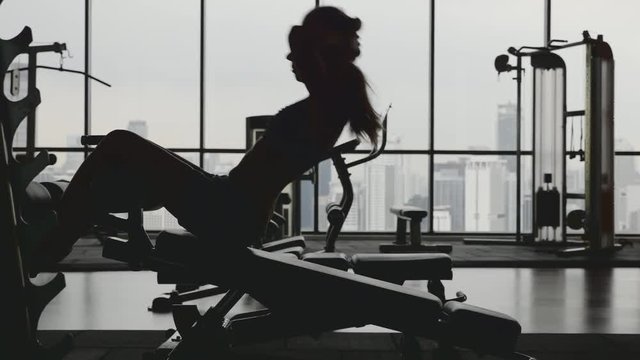 Sportswoman doing situps in gym. Muscular female athlete doing abs workout. Silhouette of slim athletic girl. Active and healthy lifestile concept. 4k shot