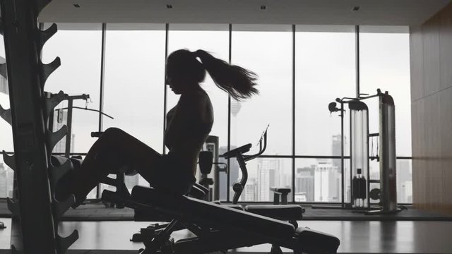 Sportswoman doing situps in gym. Muscular female athlete doing abs workout in super slow motion. Silhouette of slim athletic girl. Active and healthy lifestile concept.