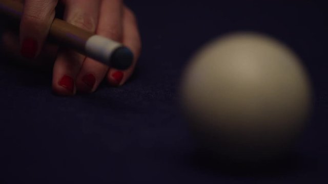 Closeup of a woman's hand hitting cue ball in pool