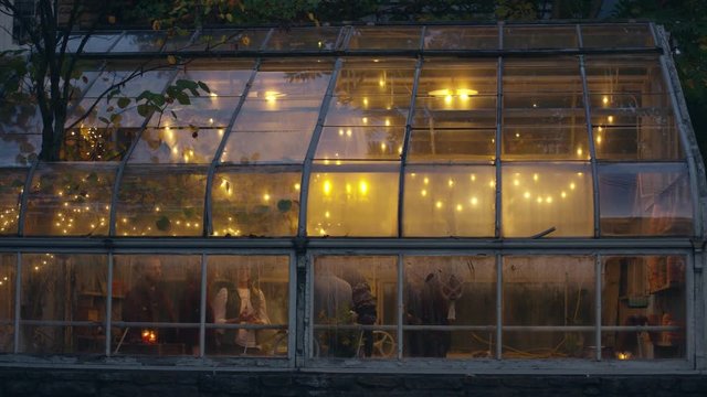 Friends dance and party in greenhouse at night, slow motion
