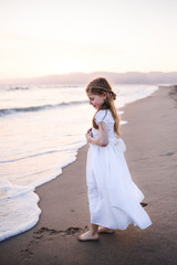 Young girl standing on the sand at the waters edge looking at the ocean trying to decide whether to go in