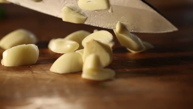 Knife cuts through garlic and parsley, close up