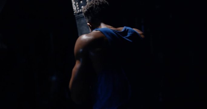 An athletic man in boxing gloves hits a punching bag