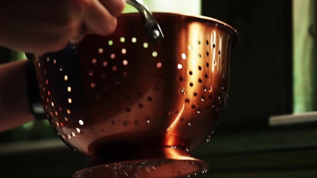 Slow motion, person washes strainer
