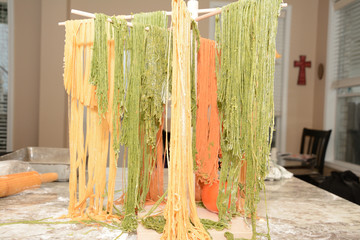 Tomato and fresh made pasta drying on wooden tree rack