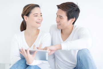 Happy loving family. Young lover couple in white bedroom. Funny man and woman having fun with tablet.