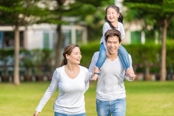 Fototapeta premium Cute Asian girl on neck parents big happy laughing and run around together.Happy family piggybacking adorable little daughter is smiling.
