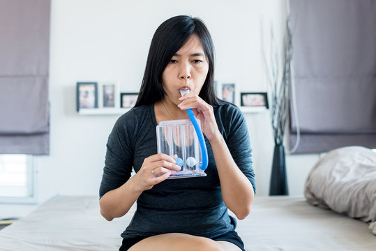 Asian woman patient using incentivespirometer or three balls for stimulate lung at home