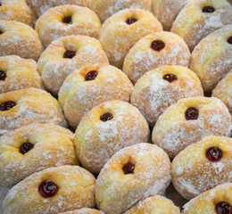Freshly made donut center filled with blueberry jam and topped with icing sugar