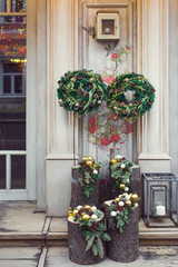 Fototapeta na wymiar Facade decoration with christmas wreaths with fir branches and cones. Greeting arrangement on entrance with beautiful New Year toys